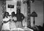 Two women and man standing next to dining table