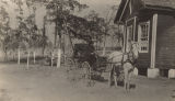 African American woman seated in a horse-drawn carriage outside a school building in rural Jefferson County, Alabama.