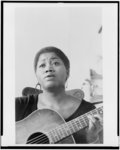 [Odetta, head-and-shoulders portrait, seated, singing with guitar]