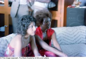 Blurry photograph of two women leaning forward while sitting on a couch