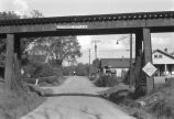 Dirt street under railroad bridge.