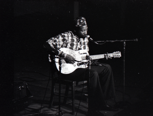 Thumbnail for Taj Mahal in concert at Northfield, Mass.: Taj Mahal seated, playing steel guitar