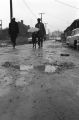 Two men and a child walking on a muddy street.