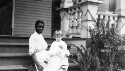 Unidentified African American woman with a white female child on her lap