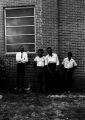 Stokely Carmichael and others, standing against the wall of a brick church building in Prattville, Alabama, during a meeting of the Autauga County Improvement Association.