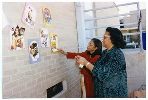 Women Taping Craft Projects on Brick Wall