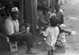 Man, woman, and children, eating and drinking outside a barn or shed near Mount Meigs in Montgomery County, Alabama.