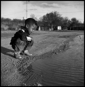 Child Squatting by a Pool of Water