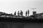 Baldwin Hills fire crew surveying a damaged roof, Los Angeles, 1985