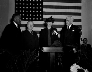 Secretary Ickes, Secretary [?] McNutt, Mrs. Roosevelt, Dr. T.E. Jones [standing in front of American flag] [black-and-white photonegative]