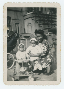 Woman posing with two small children in front of a stoop.