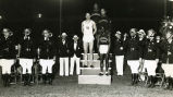 Sprinters Ralph Metcalfe and Paul Phillips with other athletes on victory stand, 1934?