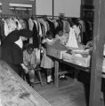 Nun assisting children as they select used clothing and shoes from racks and boxes at Nazareth Catholic Mission in Montgomery, Alabama.