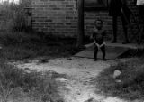 Baby standing in the front yard of a brick house in Newtown, a neighborhood in Montgomery, Alabama.