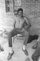 Man sitting on a wooden chair on the front porch of a brick house in Newtown, a neighborhood in Montgomery, Alabama.