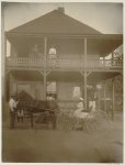 [African Americans and horse-drawn wagon in front of country store, two women stand on balcony]