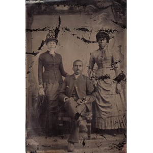 Two African American women standing next to a seated African American man