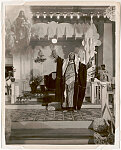 [African American preacher Daddy Grace, in Arab dress, with arms raised, and image of Christ, Harlem]