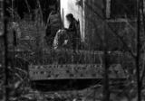 Woman sitting outside a small cinder block building in an yard beside Lincoln Cemetery in Montgomery, Alabama.