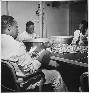 "Steward's mates joke as they dry silverware in the wardroom of U.S.S. Ticonderoga (CV-14)."