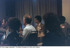 Photograph of people sitting in dining chairs