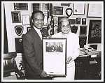 [Rosa Parks and Congressman Walter Fauntroy holding a framed picture of President Lyndon Johnson signing the Civil Rights Act of 1964]