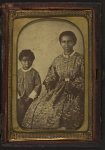 [Full-length portrait of an unidentified woman, seated, and full-length portrait of a child standing on her right, both subjects are facing front]