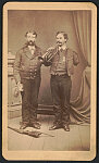 [Civil War veterans George Washington Brown of Co. B, 157th Pennsylvania Infantry Regiment, holding cartes de visite, and Edwin Silas Kellogg of Co. A, 89th New York Infantry Regiment, playing trumpet, with Spencer carbine rifle on the floor]