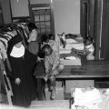 Nun assisting children as they select used clothing and shoes from racks and boxes at Nazareth Catholic Mission in Montgomery, Alabama.