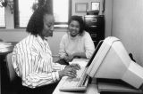 Sande Robinson types at a computer while working with a student, 1990