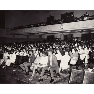 A photograph of the audience seated in an auditorium