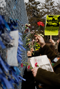 Justice for Jason rally at UMass Amherst: protesters in support of Jason Vassell placing flowers in a chain link fence