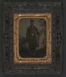 [Unidentified soldier in Union frock coat with captain's epaulettes and officer's sash with sword in front of painted backdrop showing military camp]