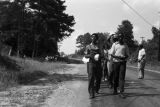 Edward Rudolph leading marchers down an unpaved road in Prattville, Alabama, during a demonstration sponsored by the Autauga County Improvement Association.