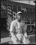 Baseball pitcher Satchel Page seated next to bleachers, Los Angeles, circa 1933