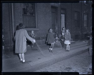 Girls playing jump rope on sidewalk : photonegative.