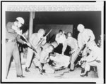 A heavily-armed group of police and national guardsmen stand ready at an open manhole after dropping a tear gas shell inside