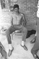 Man sitting on a wooden chair on the front porch of a brick house in Newtown, a neighborhood in Montgomery, Alabama.