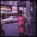 Woman in phone booth on Pike St. between 2nd and 3rd Ave., ca. 1967