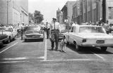 Police officer walking a dog down the center of the street during the Children's Campaign in Birmingham, Alabama.