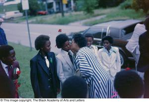 Photograph of young boy receiving a cheek kiss