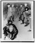 [African American man crouches on the ground and reacts to strikes from a crowd of state police with night sticks, following failed sit-in demonstration, Chester, Pa.]