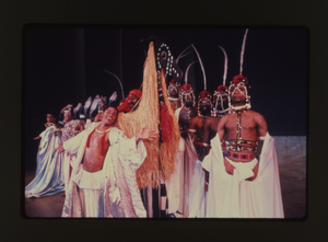 Performance slide of men in white with feather headdresses]. [color slide