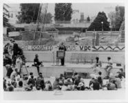 Mississippi State Sovereignty Commission photograph of John Hewlett speaking before a gathered crowd from a podium on a stage, Berkeley, California, 1964