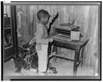 Negro child playing phonograph in cabin home. Transylvania Project, Louisiana