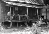 Thumbnail for Men and women on the front porch of a wooden house, observing a march in Prattville, Alabama, during a demonstration sponsored by the Autauga County Improvement Association.