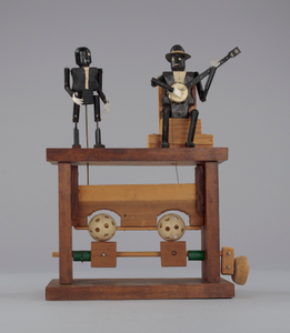 Crank toy in the form of a minstrel banjo player and minstrel male dancer