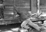 John Nixon trying to climb onto the porch of his house in Autaugaville, Alabama.