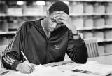 An Educational Opportunity Program student works on his homework at a table in the library, circa 1990