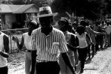 Group marching down an unpaved road in Prattville, Alabama, during a demonstration sponsored by the Autauga County Improvement Association.